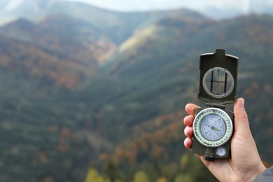 Woman using compass during journey in mountains, closeup