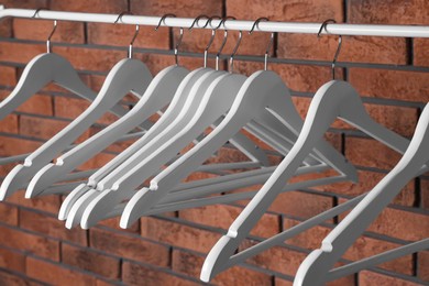 Photo of White clothes hangers on rail near red brick wall
