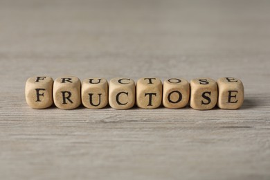 Photo of Word Fructose made of wooden cubes on table, closeup