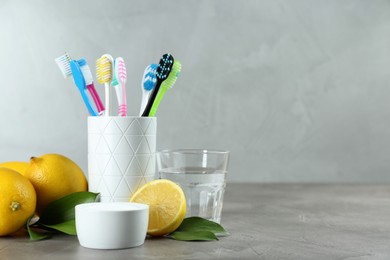 Photo of Toothbrushes, lemons and bowl of baking soda on grey table, space for text