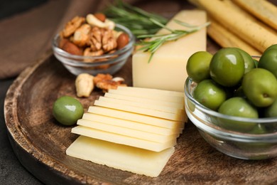 Snack set with delicious Parmesan cheese on wooden plate, closeup