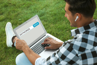 Image of Man with laptop searching for keywords outdoors