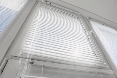 Photo of Stylish window with horizontal blinds in room, low angle view