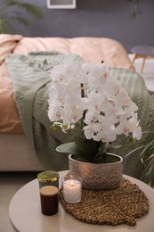 Beautiful white orchids and candles on table in bedroom. Interior design