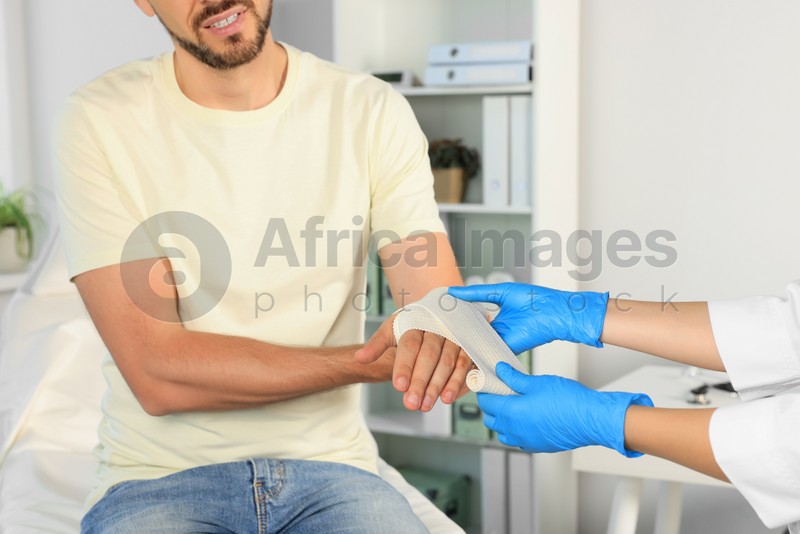 Photo of Doctor applying medical bandage onto patient's hand in hospital, closeup
