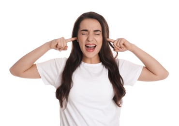 Emotional young woman covering ears with fingers on white background
