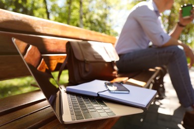 Man taking coffee break during work in park, focus on laptop