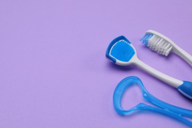 Tongue cleaners and toothbrush on violet background, above view. Space for text