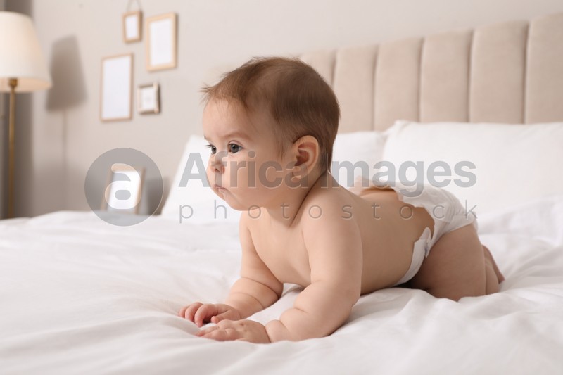 Cute little baby in diaper on bed at home