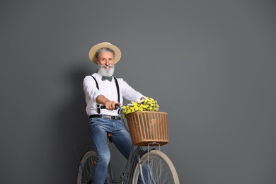Portrait of handsome mature man with bicycle on color background