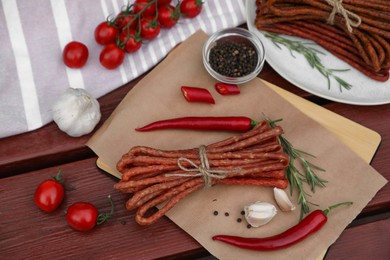 Photo of Delicious kabanosy with rosemary, peppercorn, garlic and chilli on wooden table
