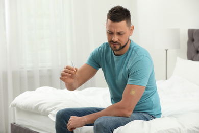 Emotional man with nicotine patch and cigarette in bedroom