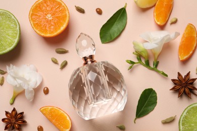 Photo of Flat lay composition with bottle of perfume, citrus fruits and flowers on pink background
