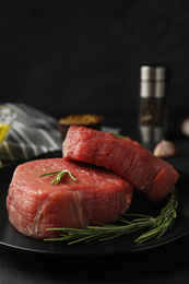 Fresh raw beef cut with rosemary on table, closeup