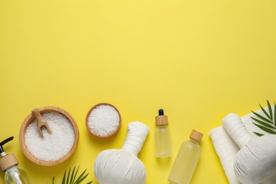 Beautiful spa composition with herbal massage bags and different care products on yellow background, flat lay. Space for text