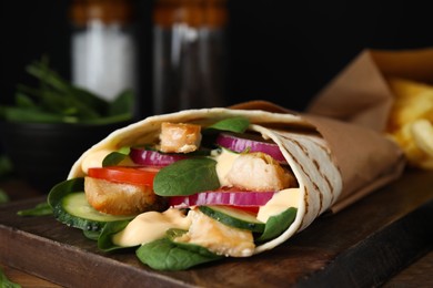 Photo of Delicious shawarma with chicken meat, fresh vegetables and spinach on wooden table, closeup