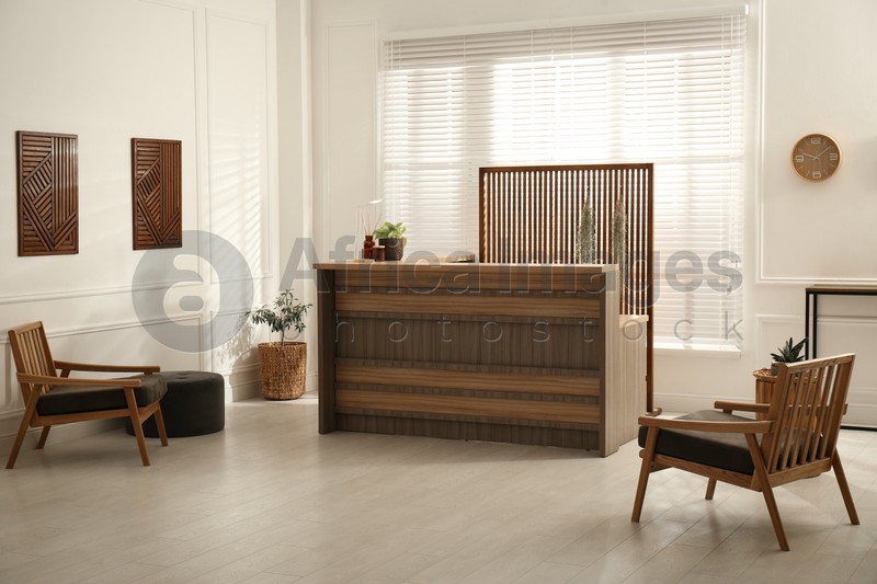 Photo of Stylish hotel lobby interior with wooden reception desk and armchairs