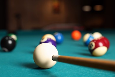 Photo of Many colorful billiard balls and cue on green table indoors, closeup