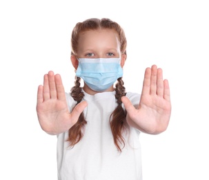 Little girl in protective mask showing stop gesture on white background. Prevent spreading of coronavirus