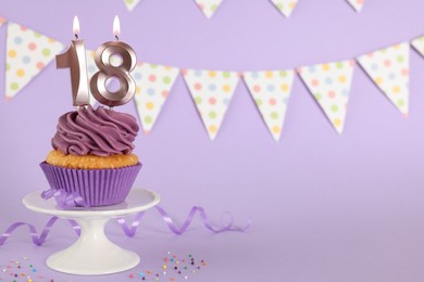 Coming of age party - 18th birthday. Delicious cupcake with number shaped candles on violet background, space for text