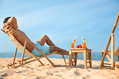 Happy man resting on sunny beach at resort