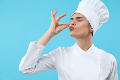 Photo of Female chef showing perfect sign on light blue background