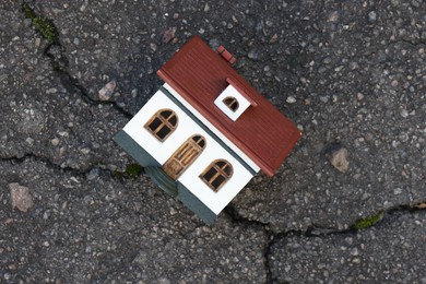 House model on cracked asphalt, top view. Earthquake disaster