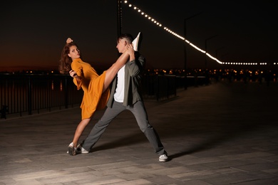 Beautiful young couple practicing dance moves in evening outdoors
