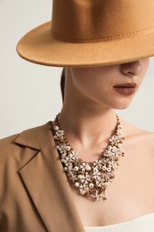 Photo of Young woman wearing stylish clothes and luxury necklace on light background