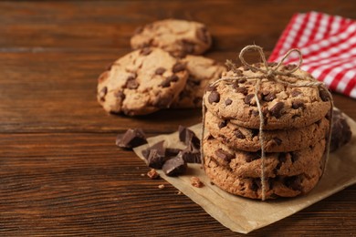 Many delicious chocolate chip cookies on wooden table. Space for text