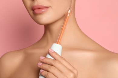 Woman using high frequency darsonval device on pink background, closeup
