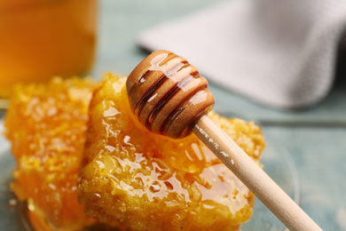 Tasty honey combs and wooden dipper on table, closeup