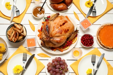 Traditional Thanksgiving day feast with delicious cooked turkey and other seasonal dishes served on white wooden table, flat lay