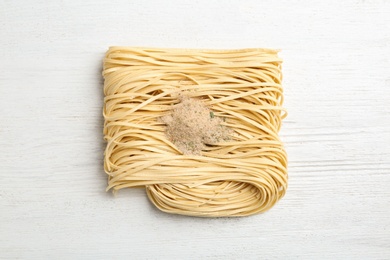 Block of quick cooking noodles with spices on wooden background, top view
