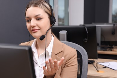 Photo of Young call center operator with headset working in modern office
