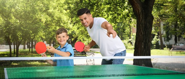 Man with his son playing ping pong in park. Banner design