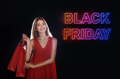 Black Friday Sale. Beautiful young woman with shopping bags on dark background 