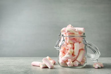 Glass jar with tasty marshmallows on light grey table. Space for text
