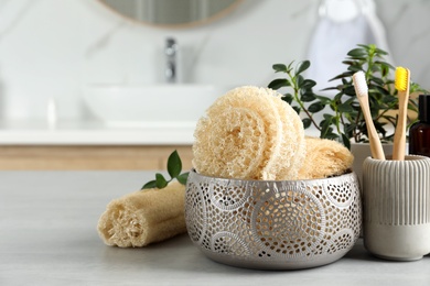 Photo of Natural loofah sponges and toothbrushes on table in bathroom. Space for text