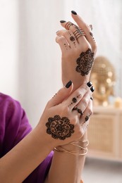 Woman with henna tattoos on hands indoors, closeup. Traditional mehndi ornament