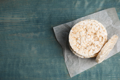 Stack of crunchy rice cakes on light blue wooden table, top view. Space for text
