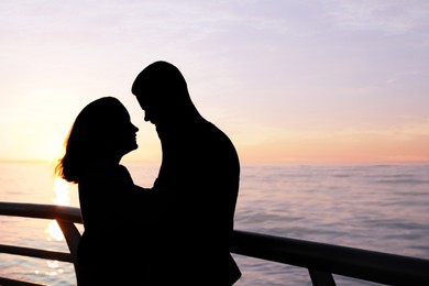 Image of Silhouette of lovely couple hugging on sea embankment at sunset