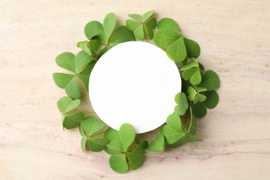 Photo of Frame of clover leaves and blank card on light table, flat lay with space for text. St. Patrick's Day celebration