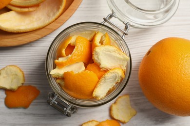 Photo of Orange peels preparing for drying and fresh fruit on white wooden table, flat lay
