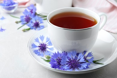 Cup of tea and cornflowers on light table, closeup