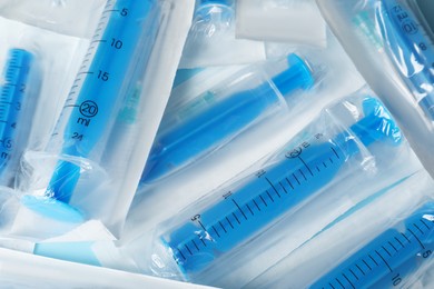 Packed disposable syringes with needles as background, above  view