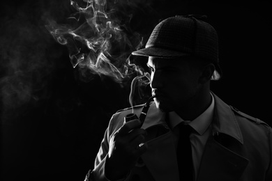 Old fashioned detective smoking pipe on dark background, black and white effect