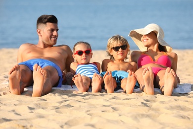 Happy family lying on sandy beach near sea. Summer holidays