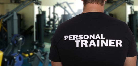 Image of Professional personal trainer in gym, space for text. Banner design