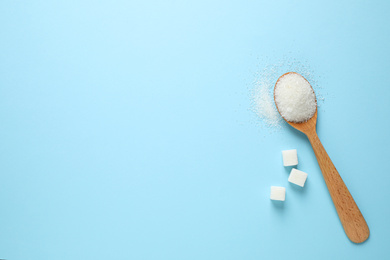 Sugar and spoon on light blue background, flat lay. Space for text